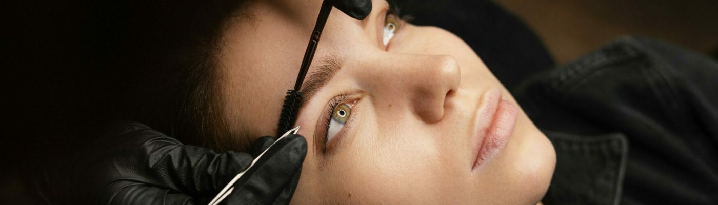 high-angle-female-clinician-doing-eyebrow-treatment-female-customer